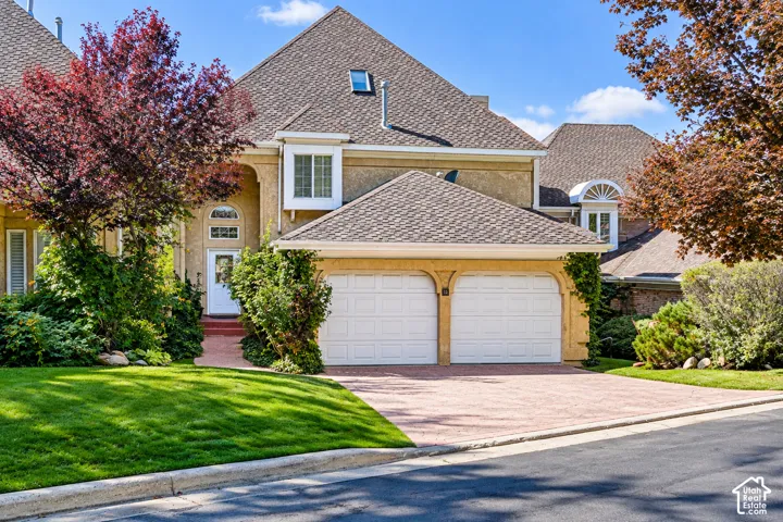 Elegant two-story residence featuring a steeply pitched gable roof with asphalt shingles, cream-colored exterior siding, and white-trimmed windows