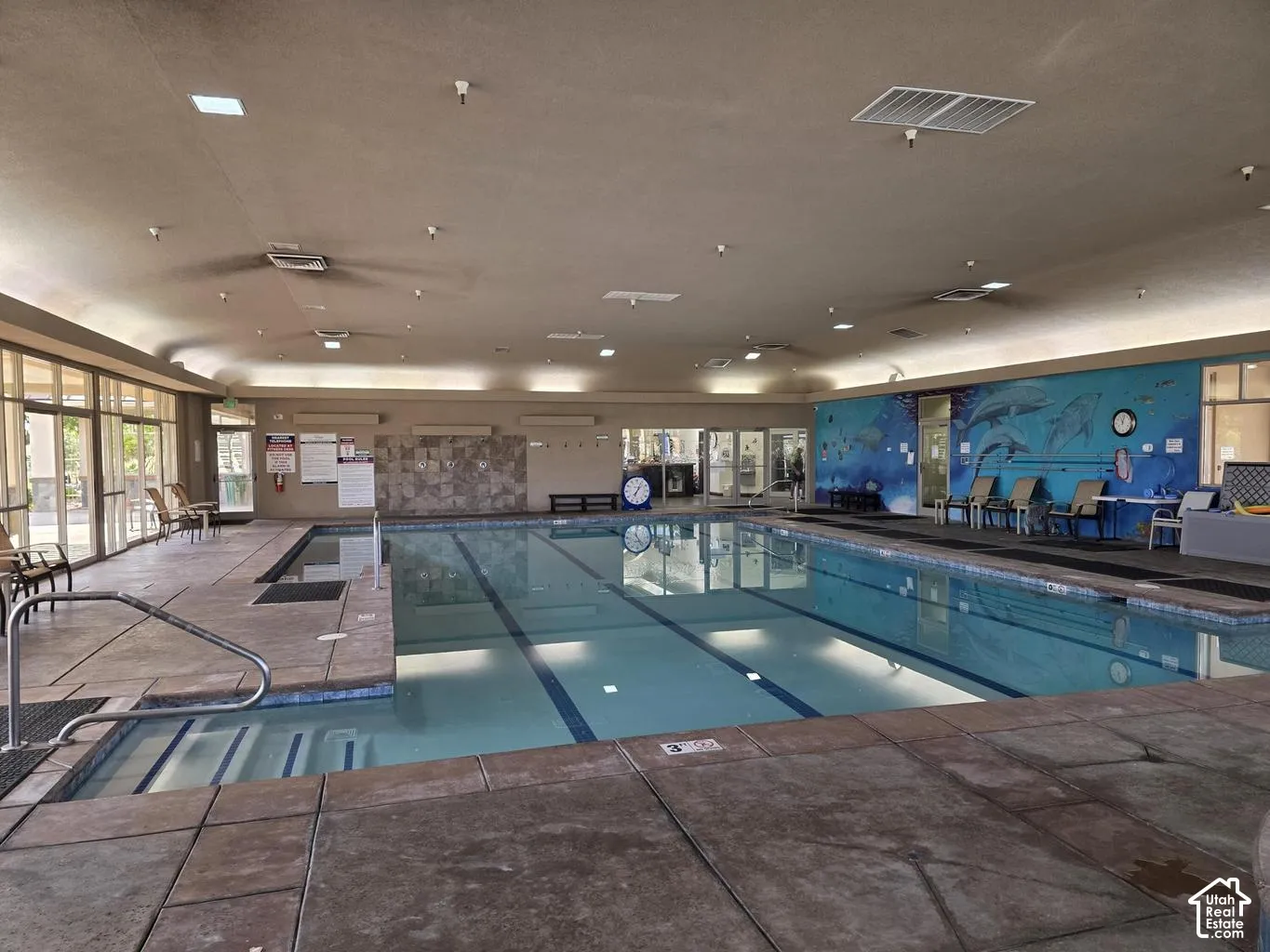 Indoor swimming pool with an integrated spa, featuring full-height windows and a decorative wall mural