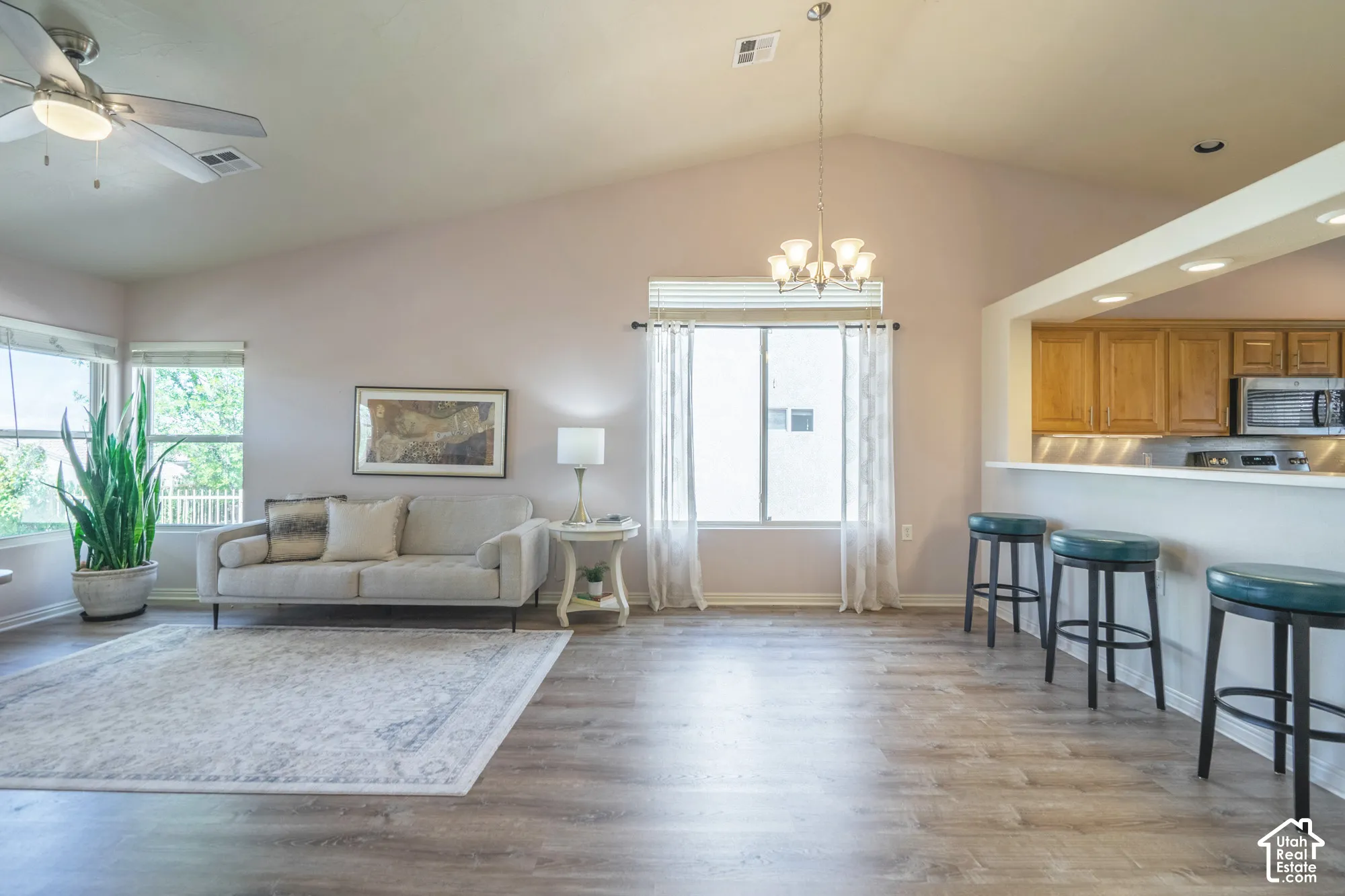 Vaulted ceiling in living and Dining Room, wood-finish flooring, multiple windows, kitchen pass-through, and recessed lighting