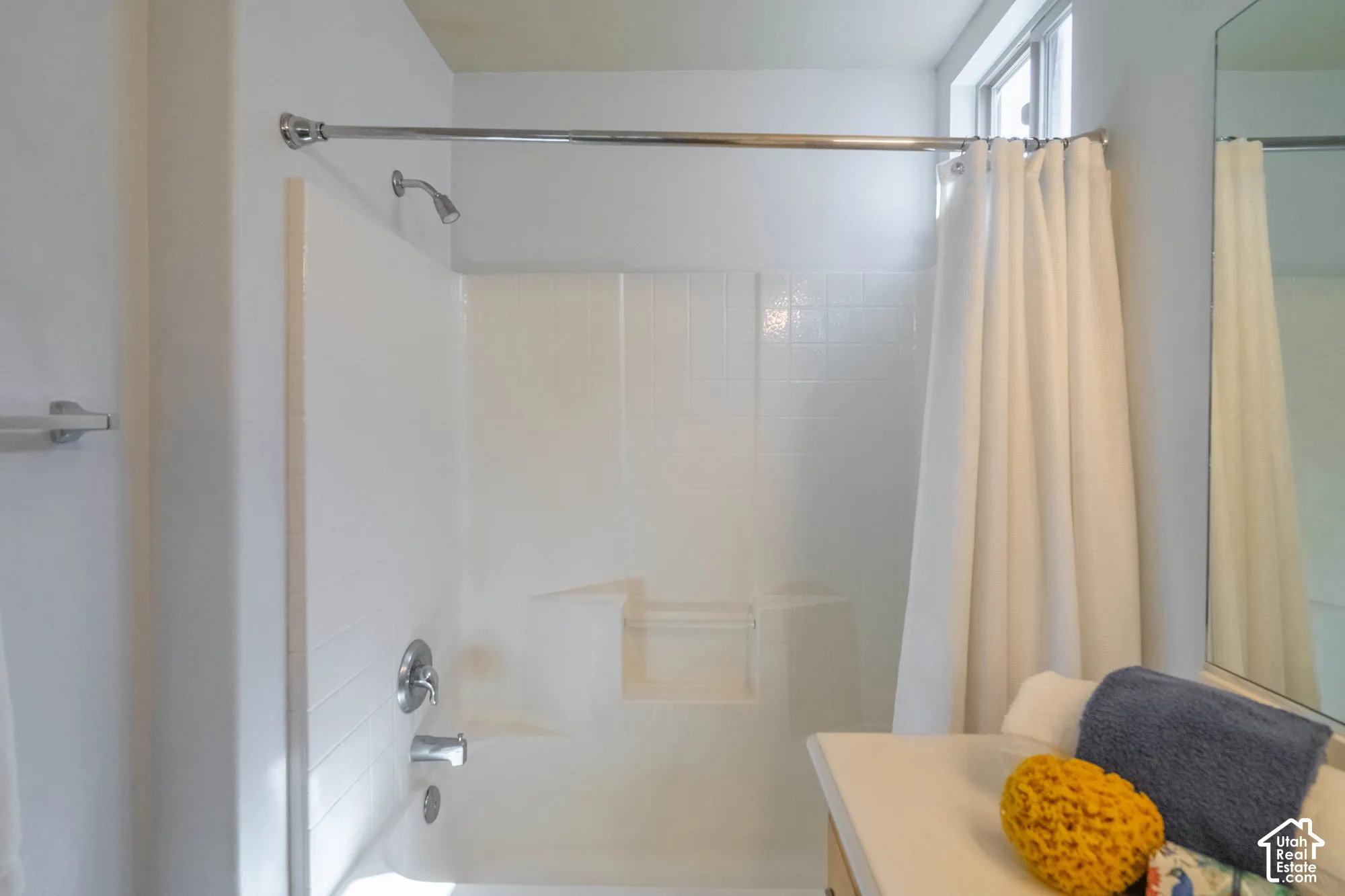 Shower/tub combination in Primary Bathroom with chrome fixtures, tiled surround, and integrated shelving