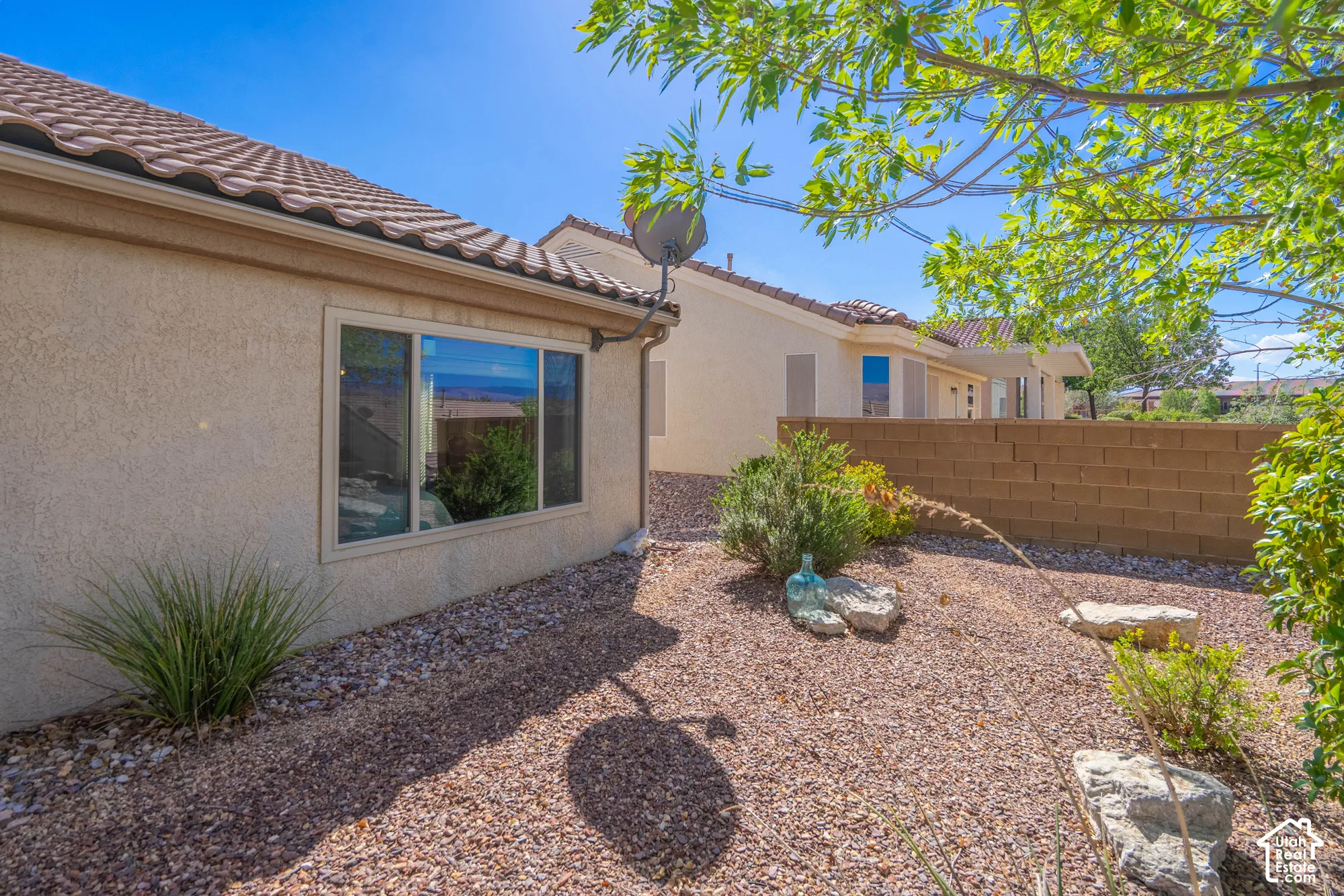 Stucco exterior with a tile roof, dual-pane window, and gravel landscaping