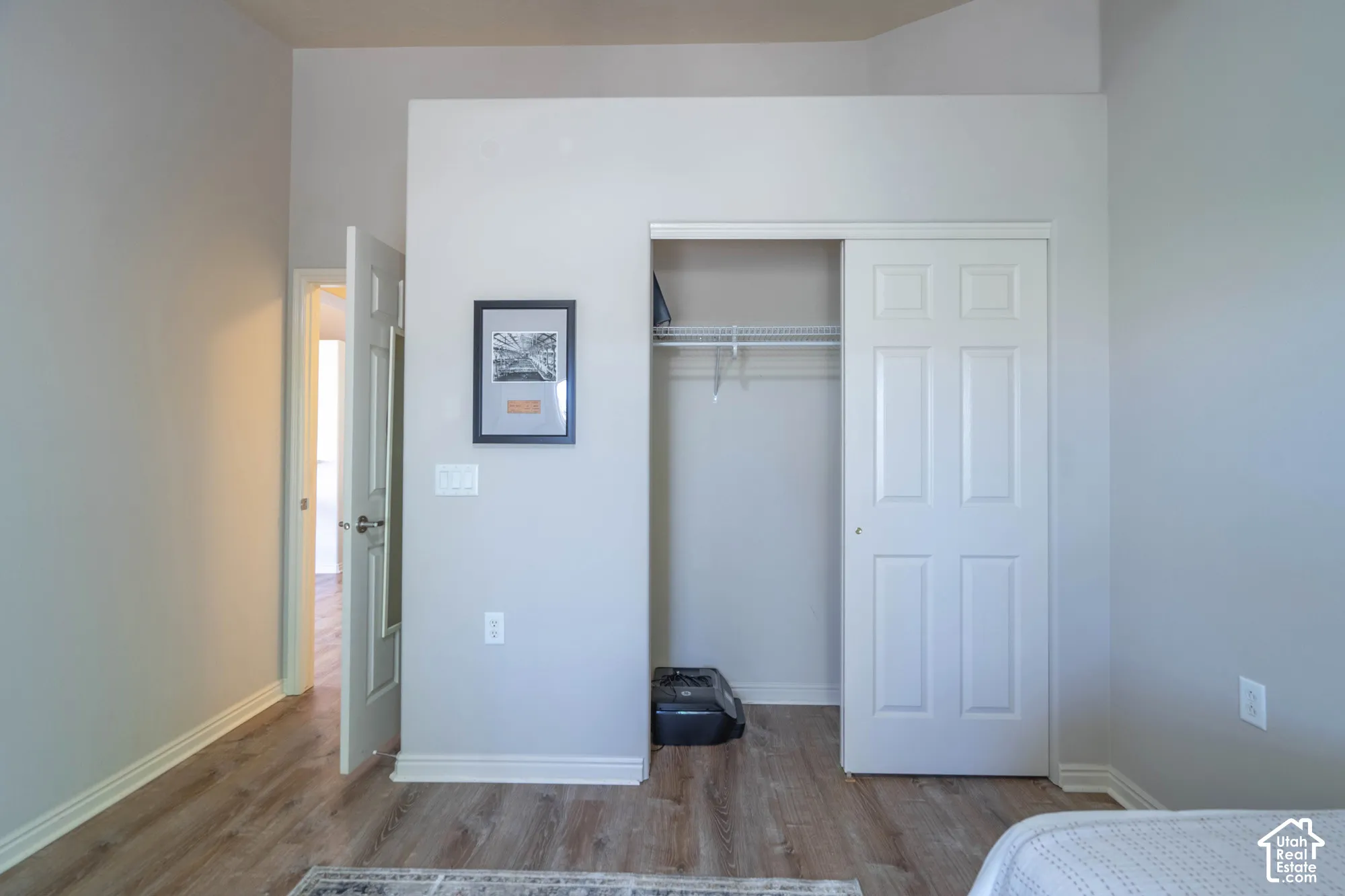Closet in 2nd bedroom with LVP flooring, white trim, sliding closet doors, and a wire closet system