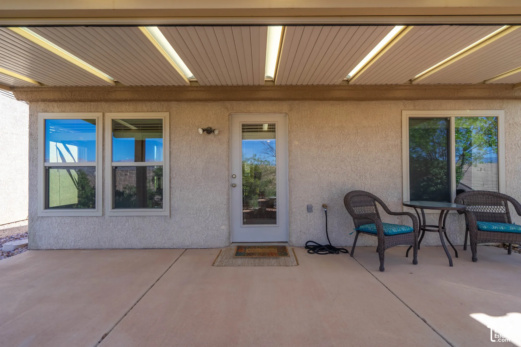 Covered patio featuring a concrete surface, overhead lighting, and textured stucco exterior