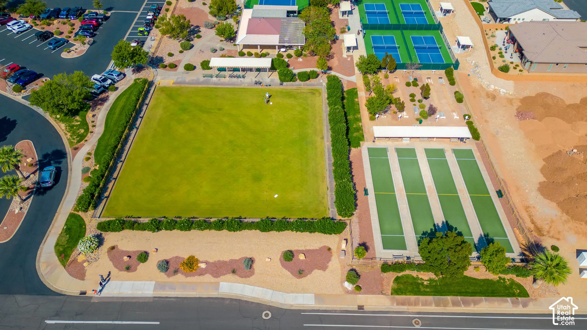 Expansive green space featuring a large lawn area, multiple tennis courts, and several bocce ball courts