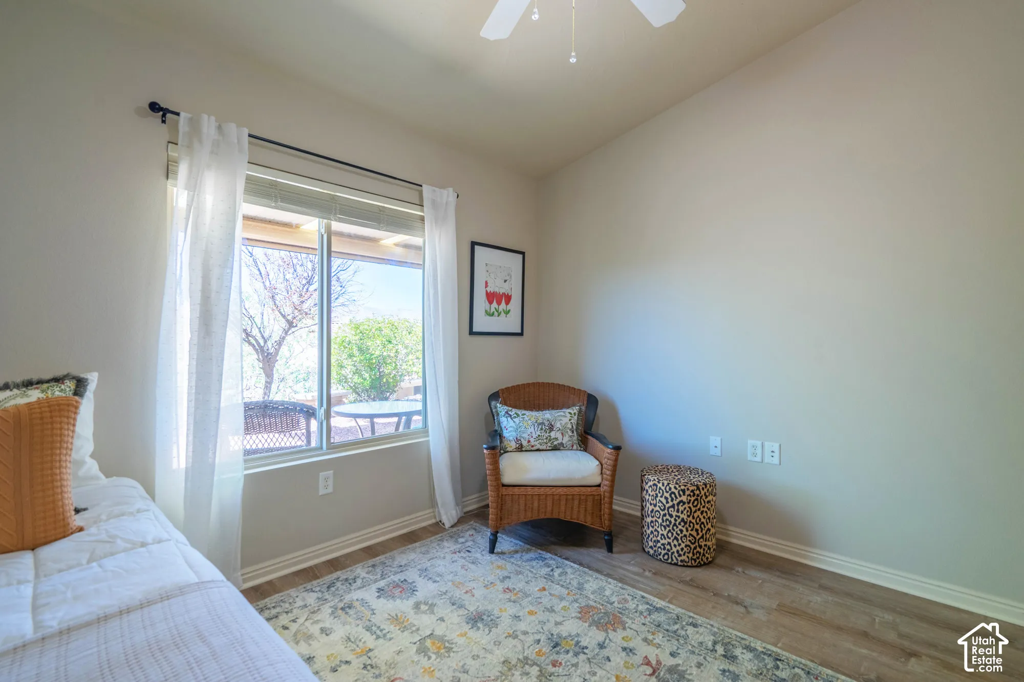 2nd Bedroom with window showing exterior patio & view, wood-finish flooring, and a ceiling fan