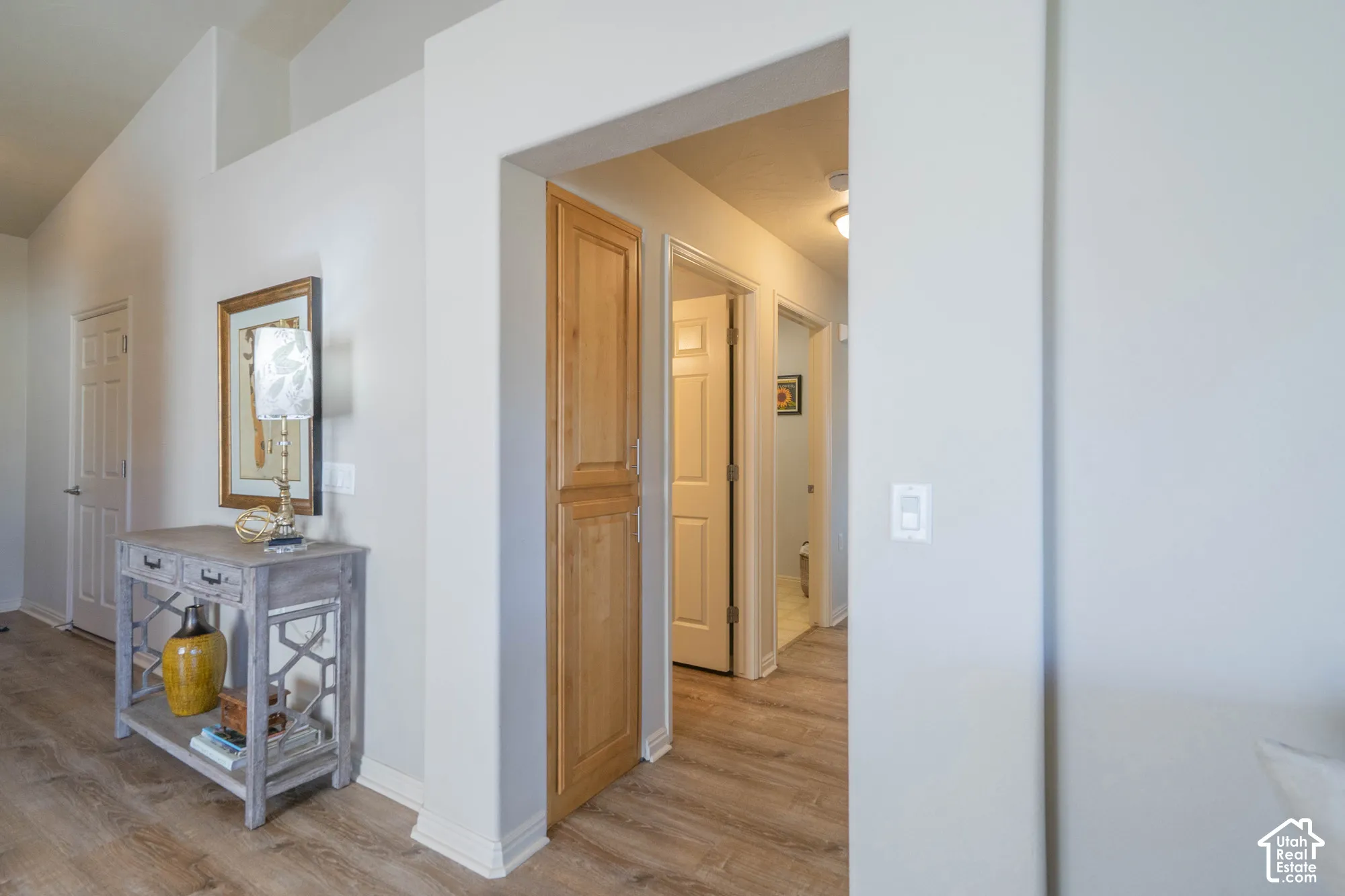 Vaulted ceiling, wood-finish flooring, light-toned walls, and a built-in wood-finish cabinet