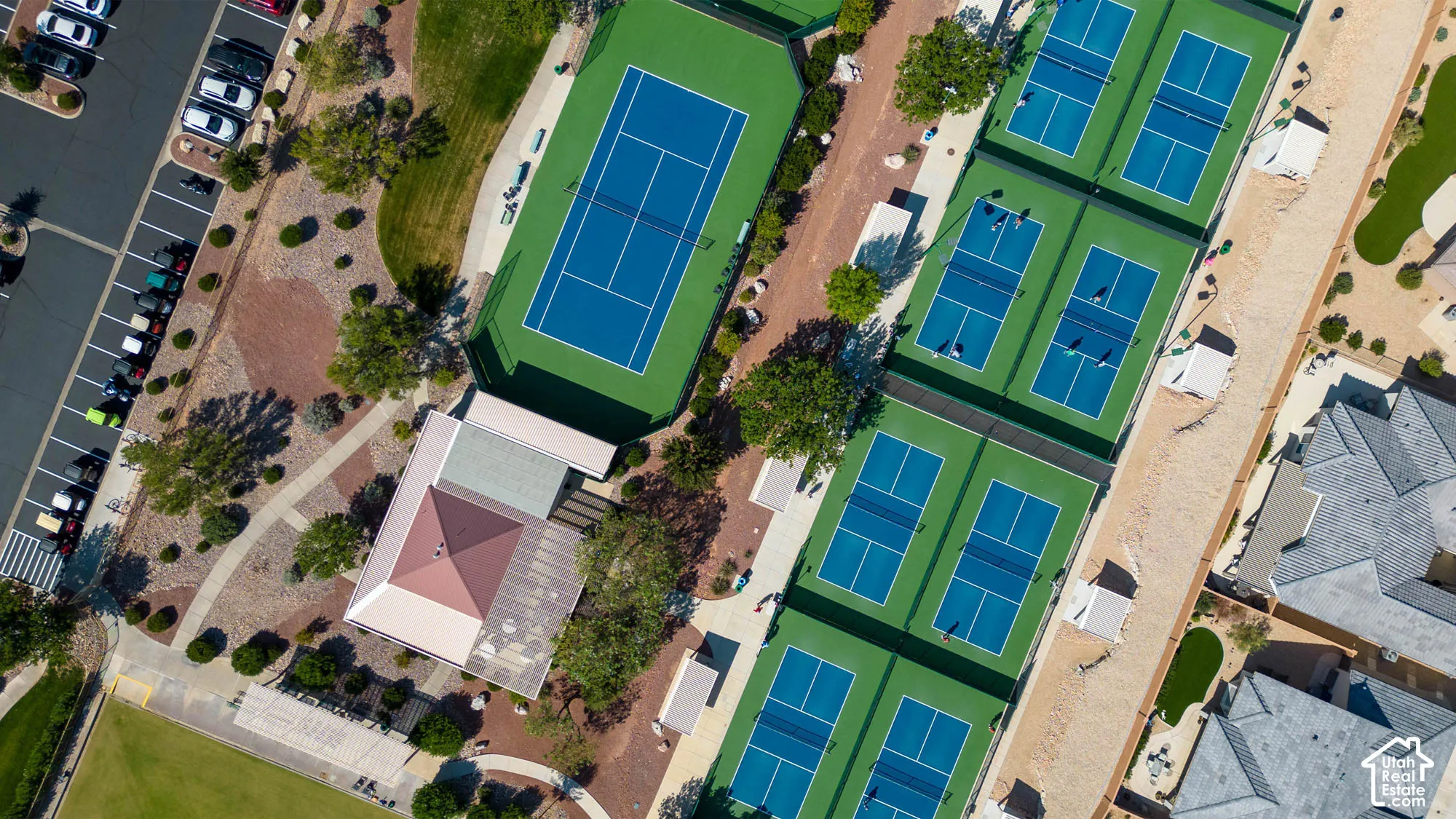 Multiple tennis courts, dedicated pickleball courts, paved parking area, covered outdoor gathering space, and mature landscaping