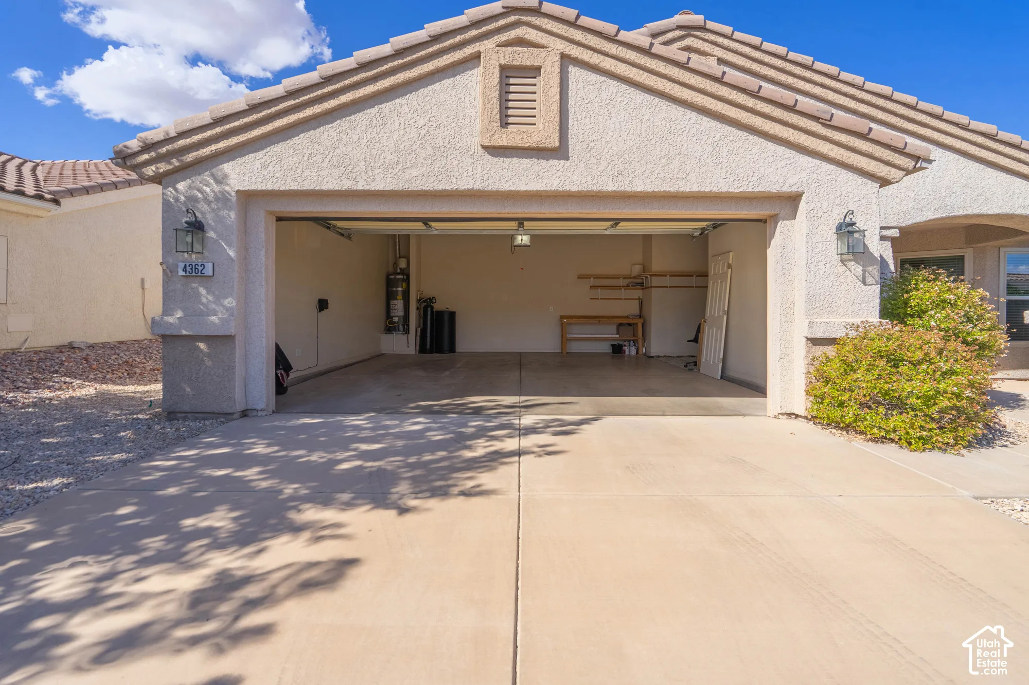 Attached garage with an exposed aggregate concrete driveway and exterior wall sconces