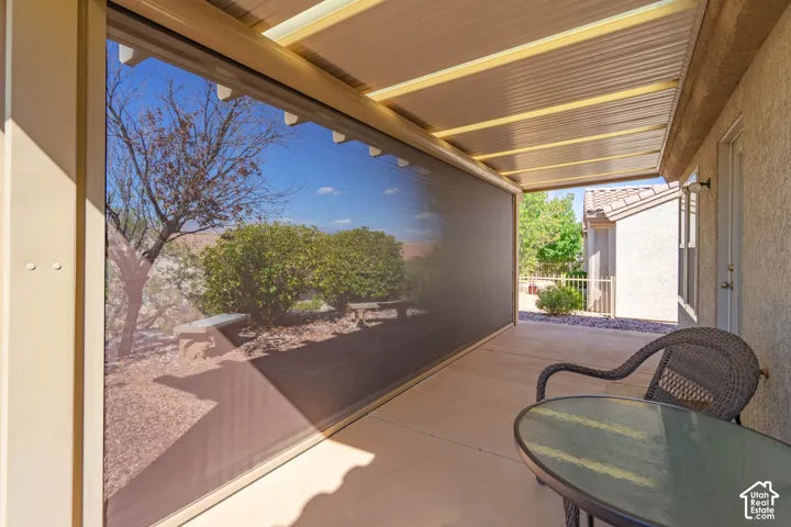 Covered patio featuring a corrugated overhead structure, retractable screen, and concrete flooring