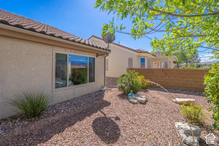 Stucco exterior with a tile roof, dual-pane window, and gravel landscaping
