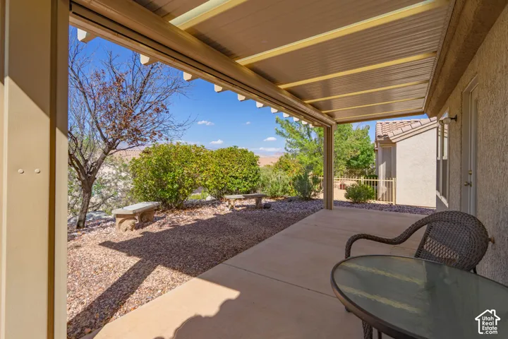 Covered patio with concrete flooring, gravel landscaping, and mature shrubbery