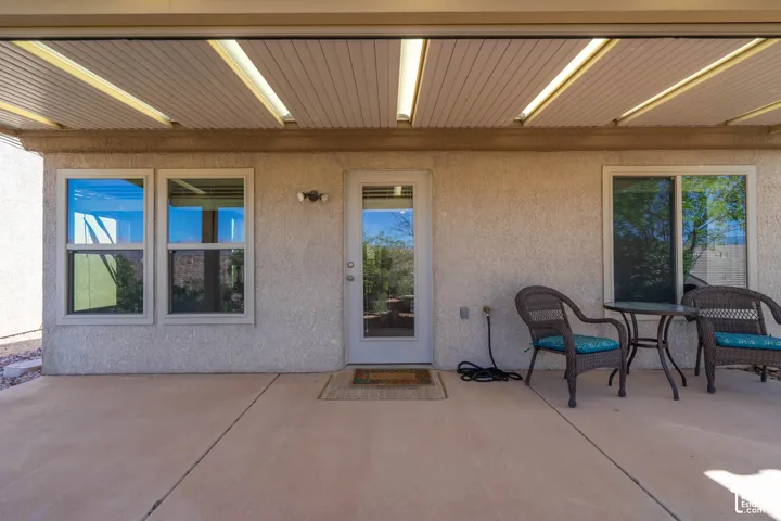 Covered patio featuring a concrete surface, overhead lighting, and textured stucco exterior