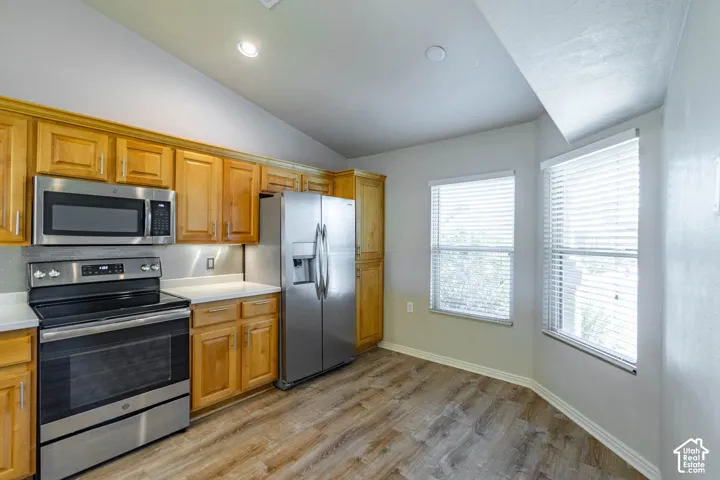 Kitchen featuring wood-finish cabinetry, stainless steel appliances, light-toned countertops, and wood-finish flooring. Eat-in Breakfast Nook