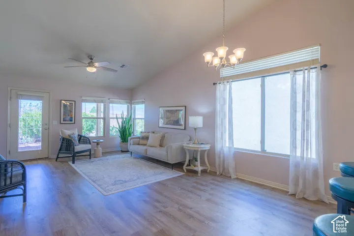 Living and Dining Room with vaulted ceiling with an attached ceiling fan, wood-finish flooring, multiple large windows, and a glass-paneled door