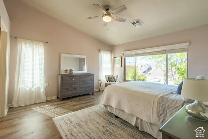 Primary Bedroom with Vaulted ceiling with a ceiling fan, wood-finish flooring, and large windows with blinds