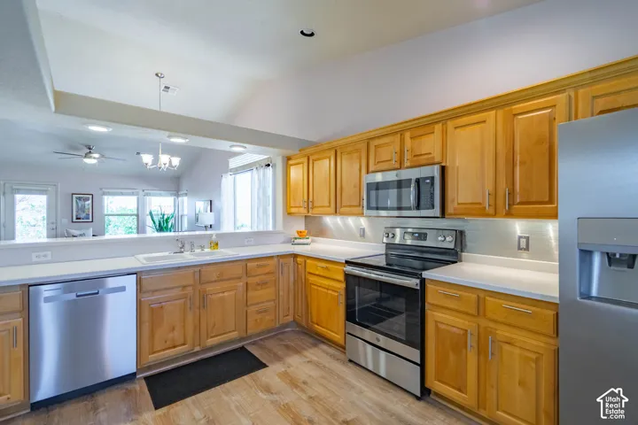 Kitchen featuring wood-finish cabinetry, stainless steel appliances, light-toned countertops, and wood-finish flooring