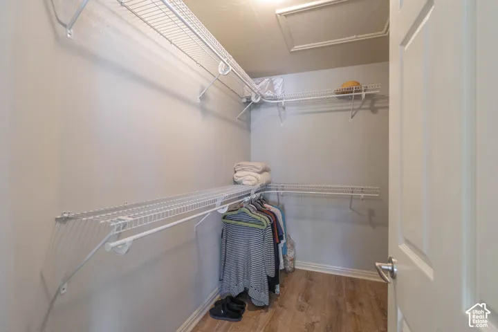 Walk-in closet with multiple wire shelving units and hanging rods, wood-finish flooring, and a paneled door with brushed nickel hardware