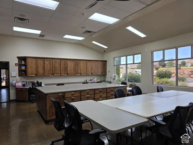Craft Room with Vaulted ceiling with recessed lighting and ceiling fan, extensive wood-finish cabinetry, built-in central island with drawers, and multiple large windows