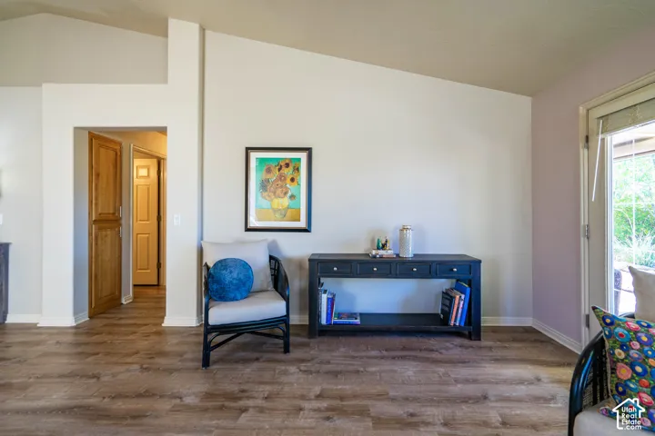 Wood-finish flooring throughout, vaulted ceiling, built-in wooden cabinetry, white trim, and direct outdoor access