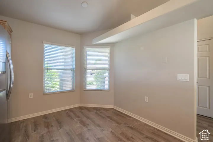 Wood-finish flooring, two large windows with blinds, recessed ceiling lighting, in the kitchen nook