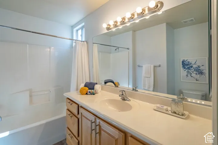 Primary Bathroom vanity with integrated sink, wood-finish cabinetry, and a full-width mirror