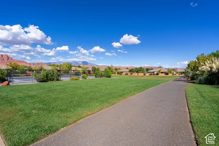 Expansive manicured lawn with mature landscaping and established trees, complemented by a paved walkway and mountain vistas in the distance