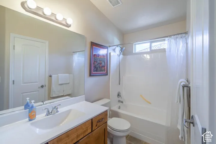 Vanity with wood-finish cabinetry, white countertop, and integrated sink