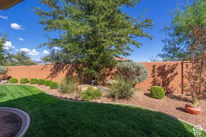 Manicured lawn with concrete curbing, surrounded by a rock and shrub-lined perimeter