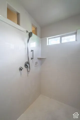 Shower stall with chrome fixtures, built-in grab bar, and integrated shelving