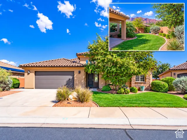 Stucco exterior with a tiled roof, stone masonry accents, concrete driveway, two-car garage, and landscaped lawn featuring desert flora