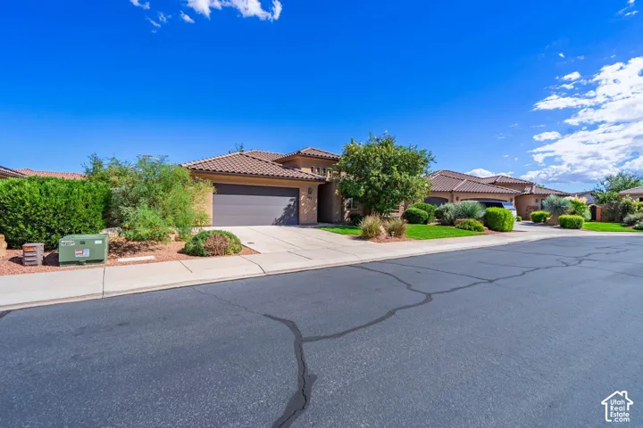 Stucco exterior with a tile roof, an integrated garage, and a concrete driveway