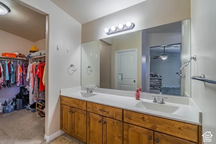 Dual-sink vanity with wood-finish cabinetry and white countertop, complemented by an oversized framed mirror and contemporary lighting fixture