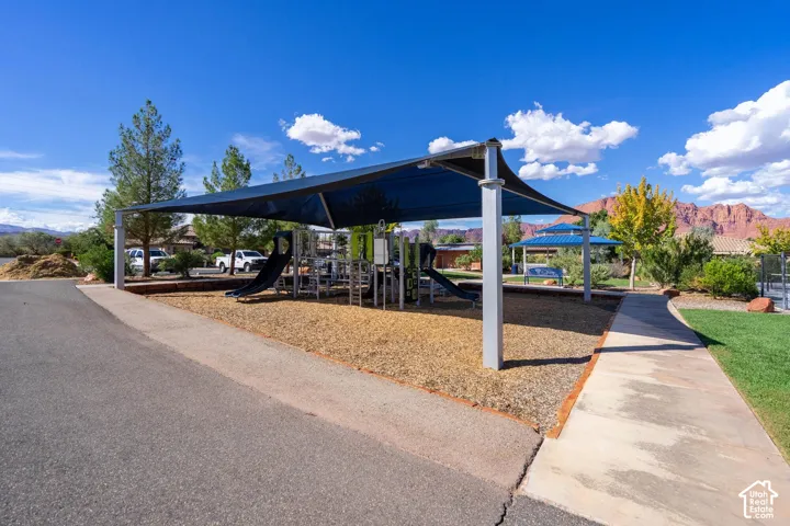 Community playground with sun shade structure, wood chip ground cover, and a concrete pathway