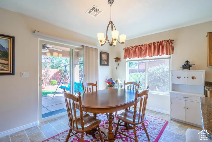 Bright dining room featuring a round wood-finish table, tile flooring, and a decorative area rug