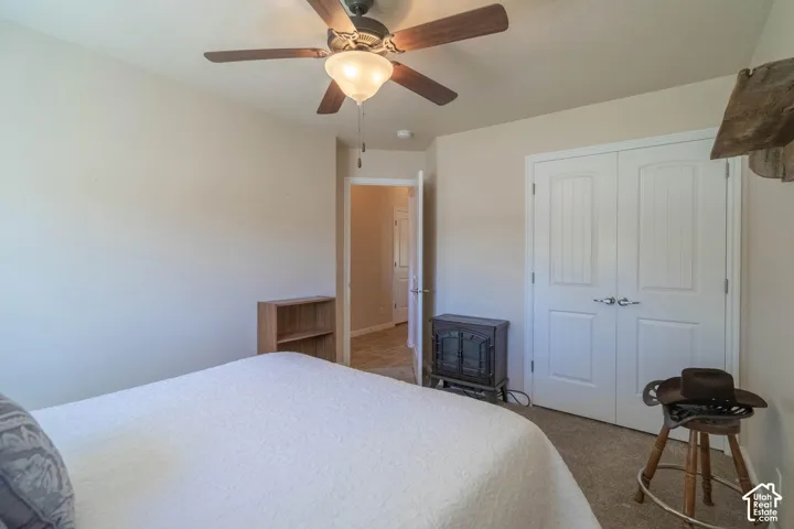 Ceiling fan with integrated lighting, carpeted flooring, and white paneled bi-fold doors