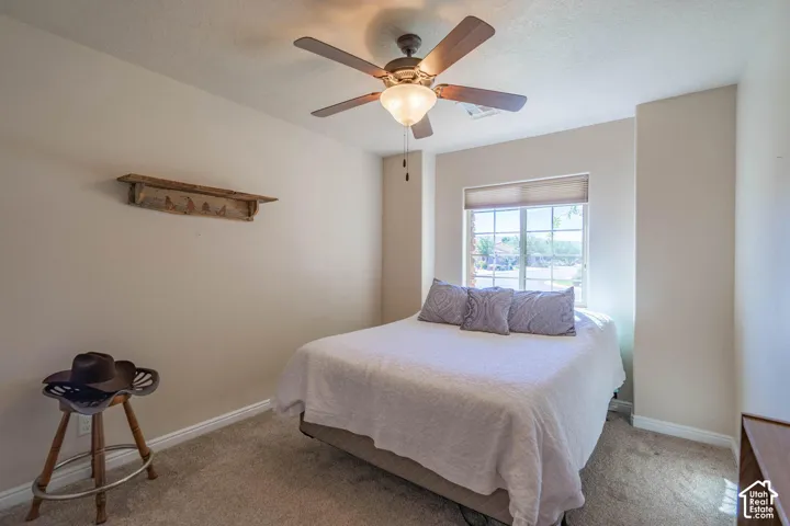 Carpeted room featuring a ceiling fan with integrated lighting, a window with a roller shade, and neutral wall tones