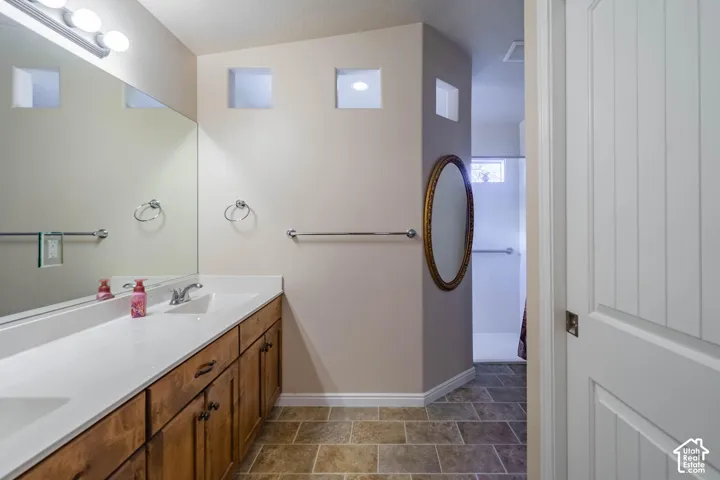 Spa-inspired primary bathroom featuring a wood-finish vanity with dual sinks, white quartz countertop, and brushed nickel fixtures