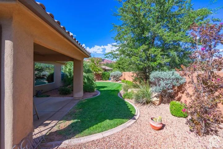 Covered patio with a concrete surface, bordered by a manicured lawn and a gravel landscape