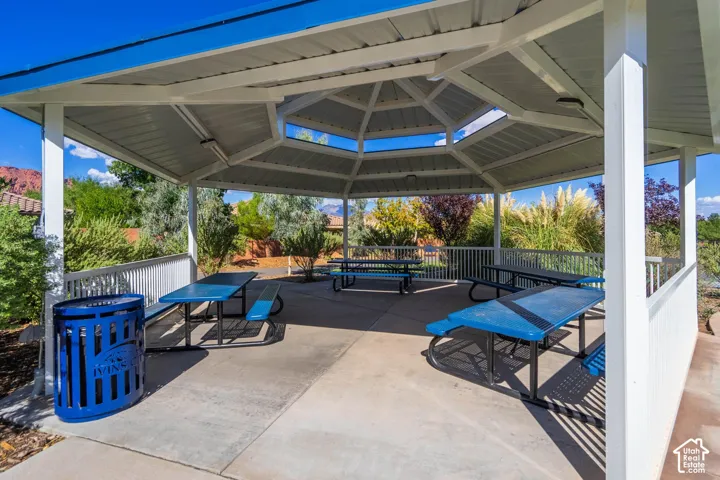 Covered outdoor pavilion with concrete flooring, white railings, and mature landscaping