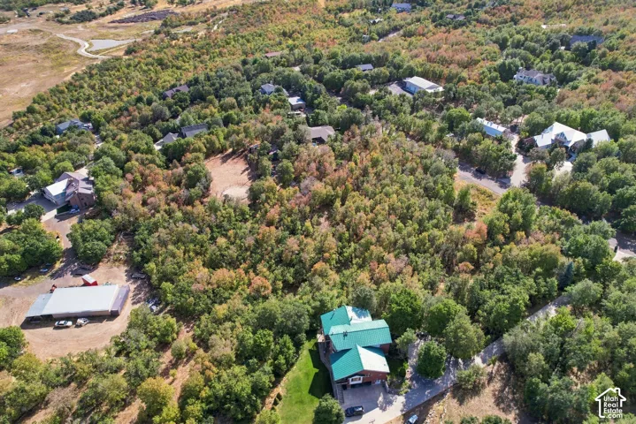 Property featuring a multi-story residence with a green roof, surrounded by mature trees