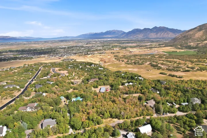Expansive aerial landscape featuring a residential area, distant water body, and surrounding mountains