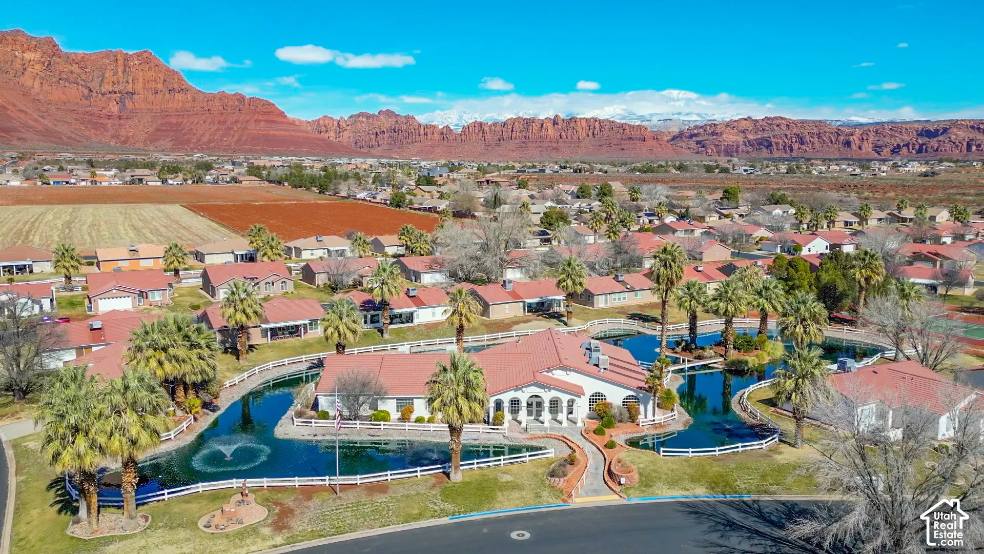 Community with central water features, surrounding residences, and a backdrop of mountainous terrain