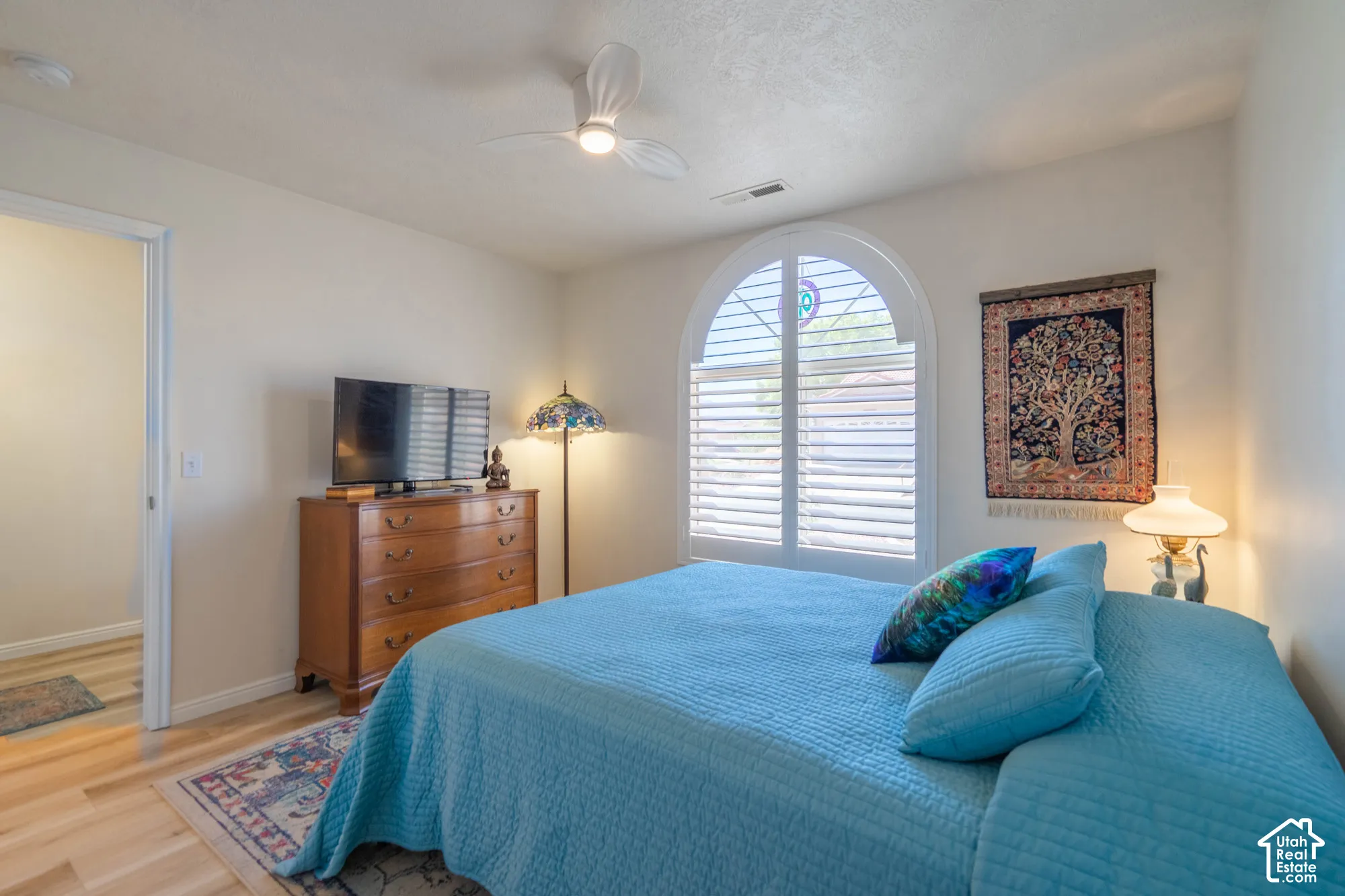 Arched window with plantation shutters, ceiling fan, wood-finish flooring, and recessed lighting