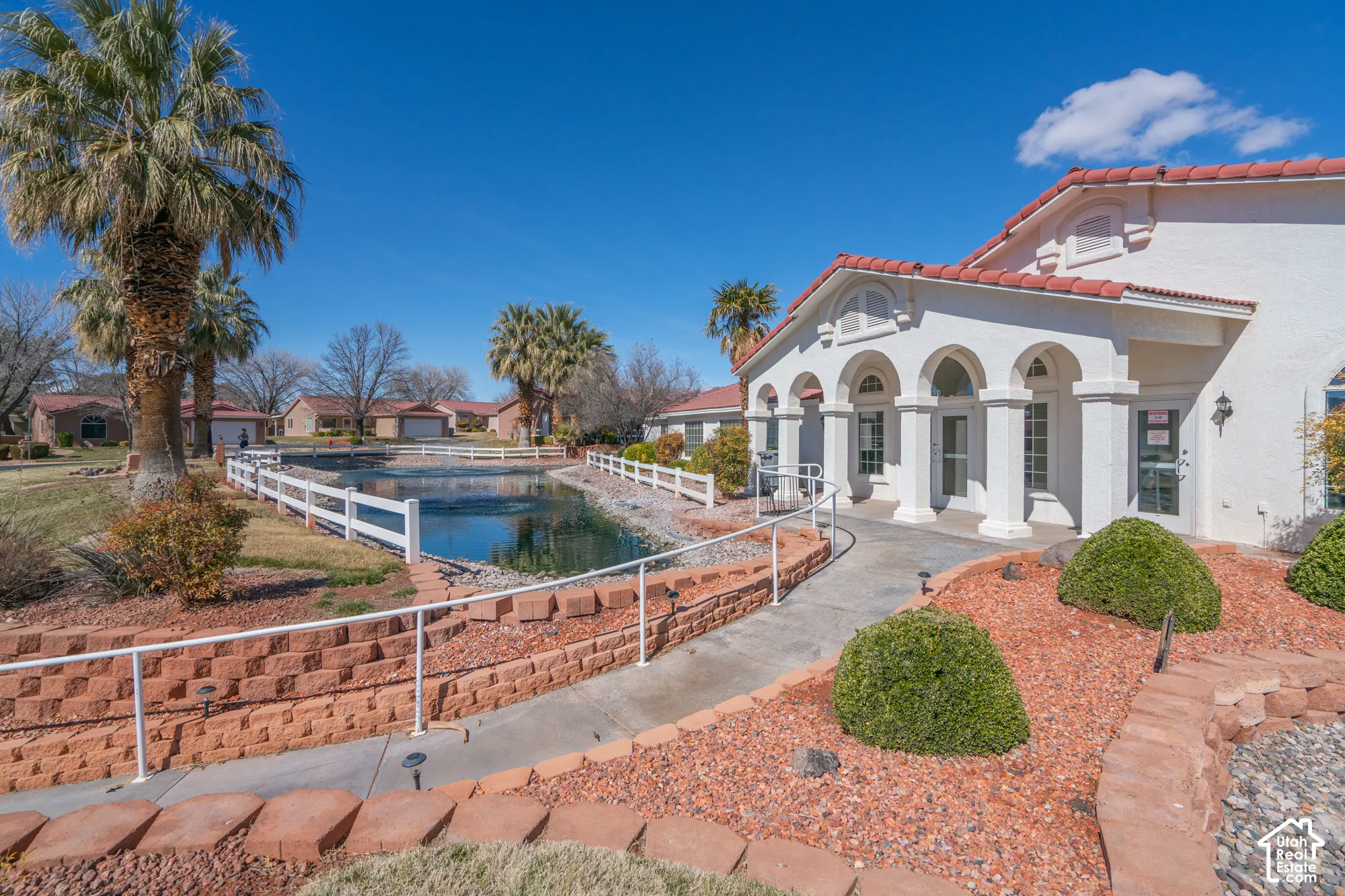 Exterior with white stucco finish, red tile roof, arched entryways, and palm trees
