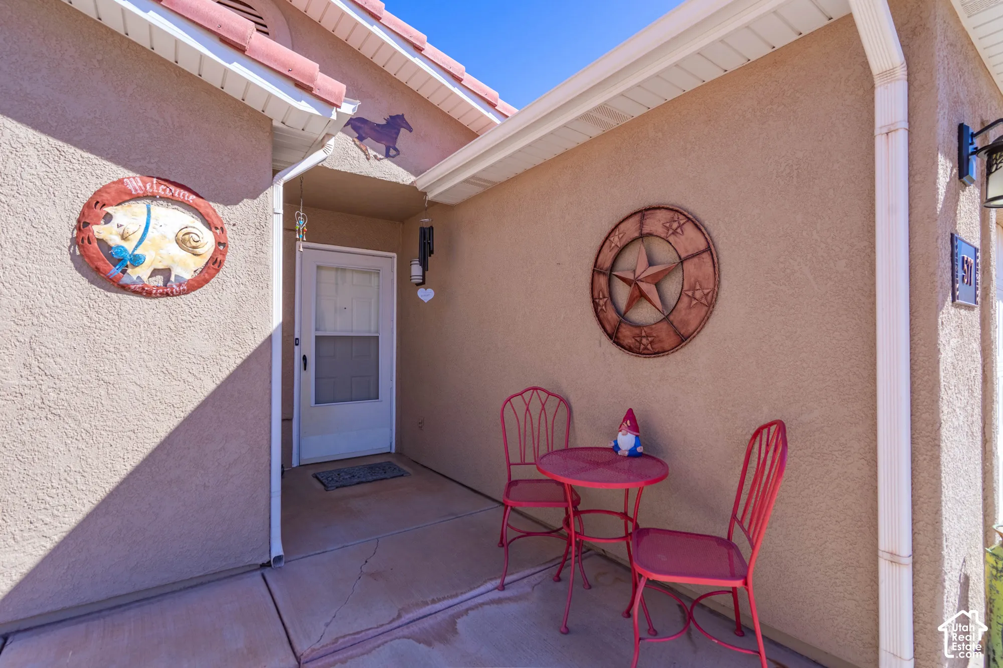 Stucco exterior with a tiled roof, covered entry, and exterior lighting fixture