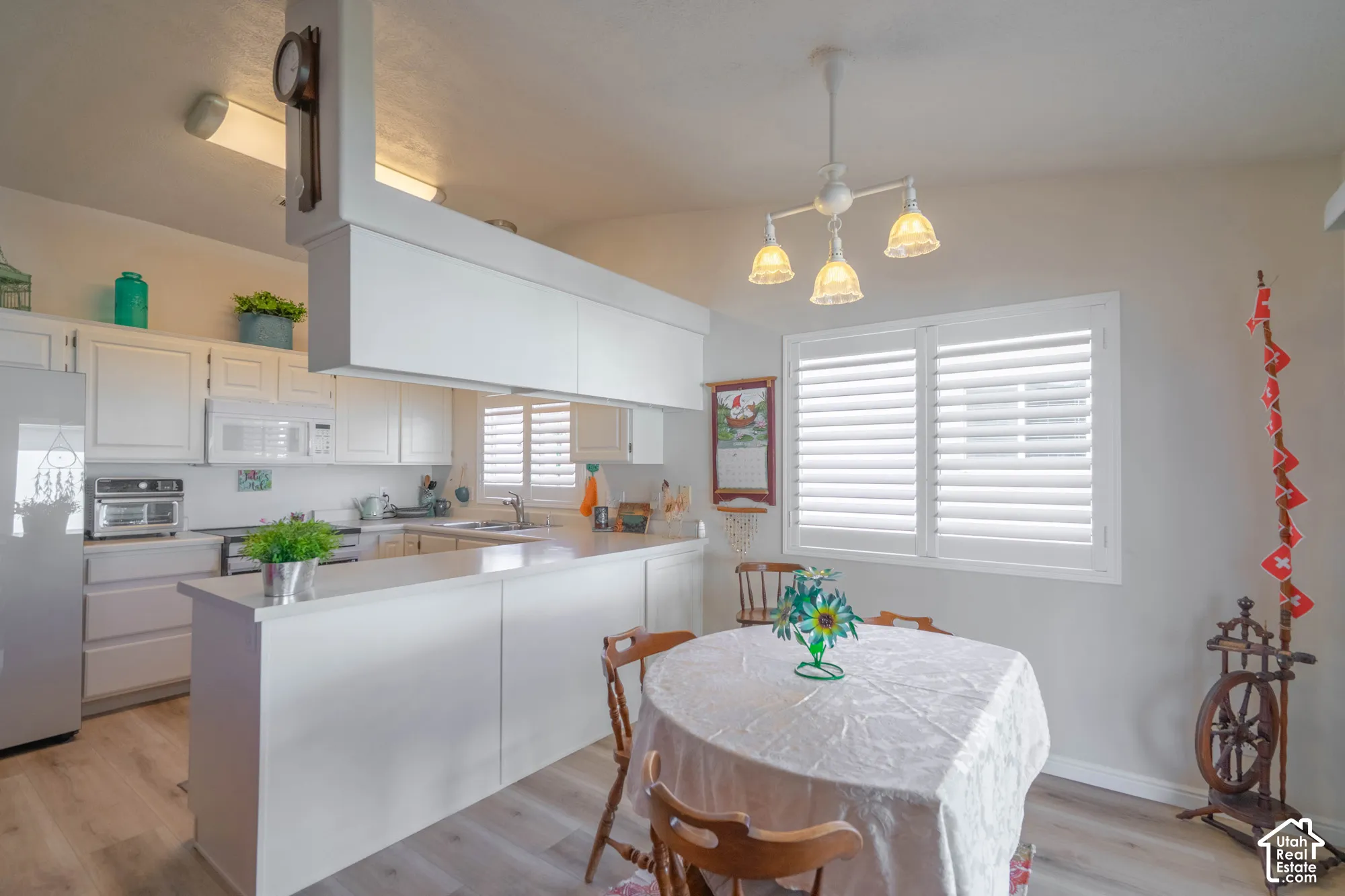 Kitchen with white cabinetry, wood-finish flooring, white appliances, and a peninsula countertop