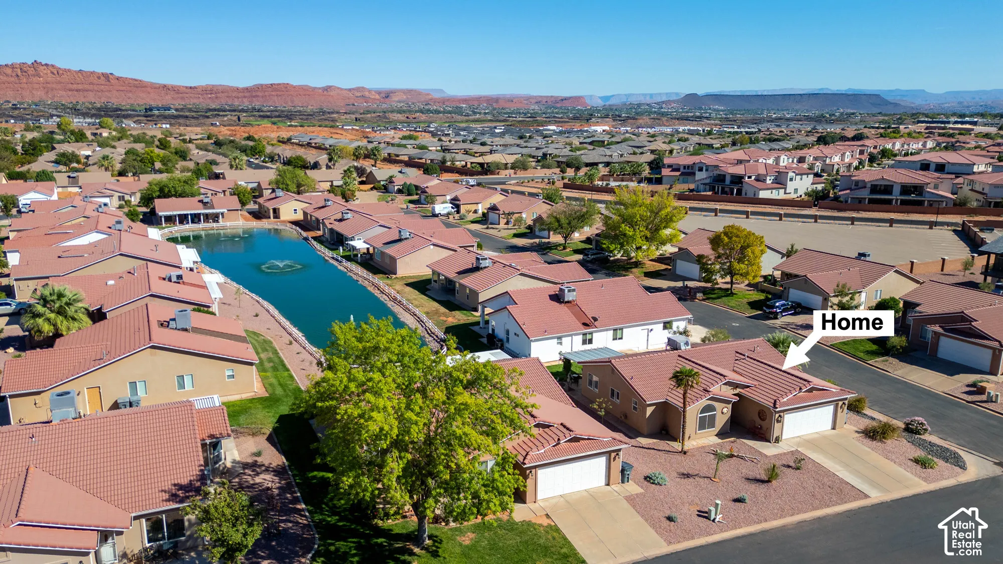 Community featuring a central pond with a fountain, surrounded by residential properties with red-tiled roofs