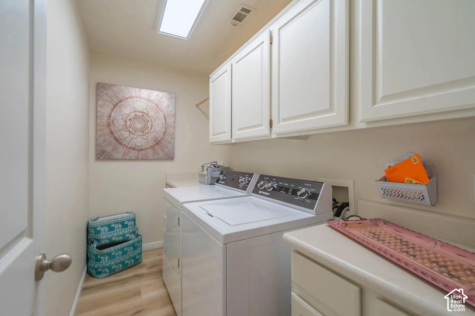 White cabinetry, light countertop, wood-finish flooring, and a ceiling light fixture