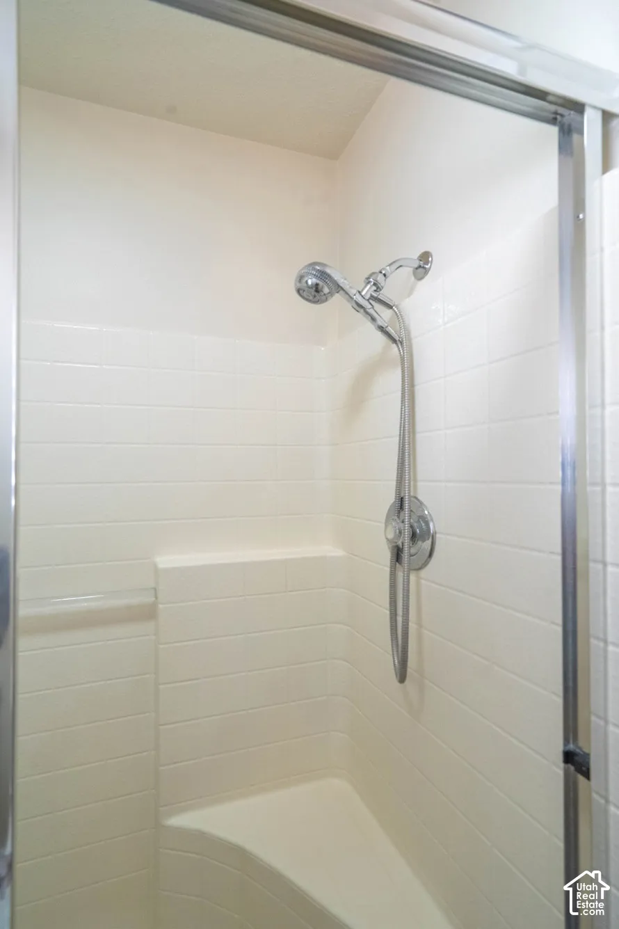 Shower stall with a built-in bench, integrated shelving, and a chrome-finish shower head with an additional handheld spray