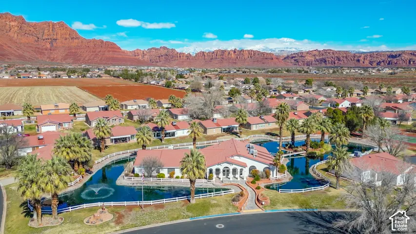 Community with central water features, surrounding residences, and a backdrop of mountainous terrain